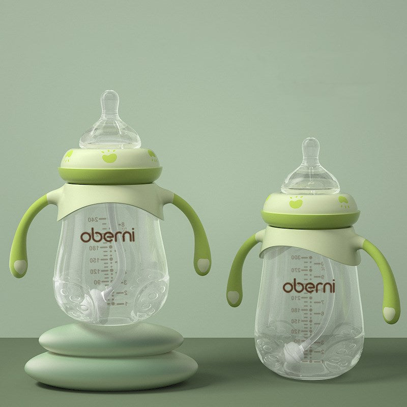 Two green-handled baby feeding bottles on a soft green background